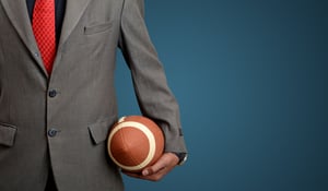 Professional Suited Man with american football ball on blue banner background.