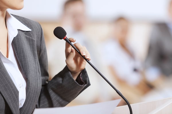 Businesswoman standing on stage and reporting for audience-1