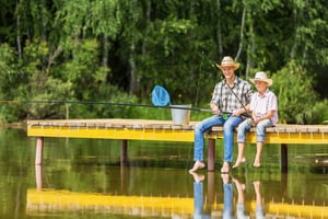Father and son sitting on bridge and fishing