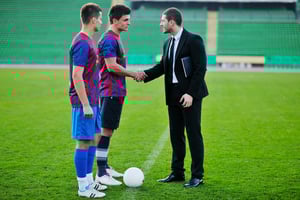 soccer  sport manager in business suit coach and football player on stadium with green grass and white ball